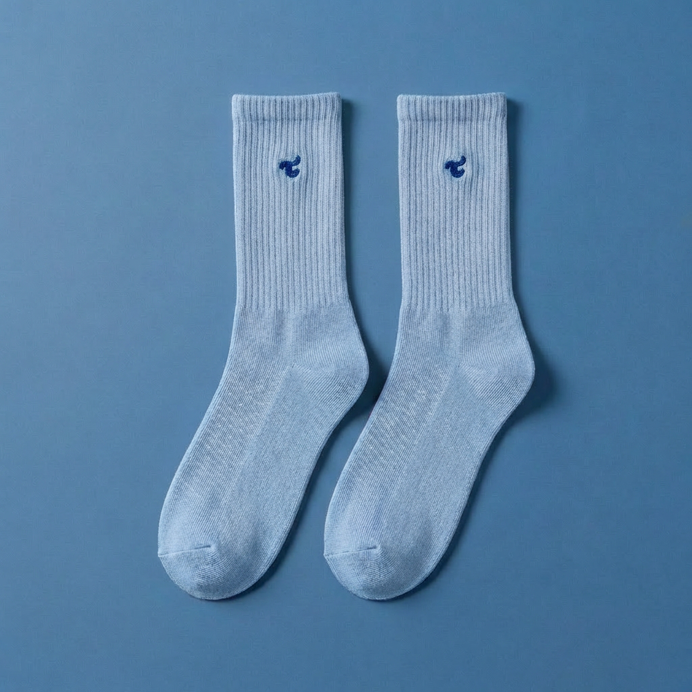 A pair of Tiny Socks in Soft Marina, laid flat on a blue background.