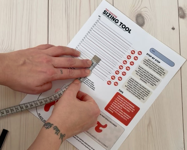 Hands measuring the distance between heel and toe mark with a tape measure.