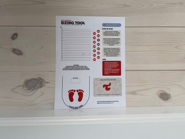 The Tiny Dancers sizing tool printed and placed against a wall.