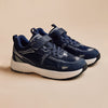 A pair of Play Junior in navy, three-quarter view on a warm beige background.