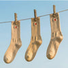 Three pairs of Tiny Socks in Sugar Swizzle hanging on a clothesline against a blue sky.
