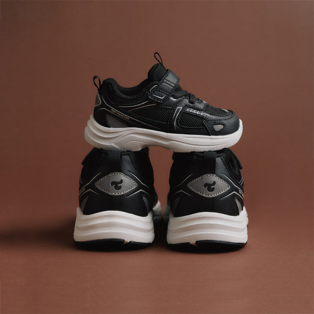 A pair of Play Infant in black, front and rear view on a warm brown background.