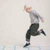 Child mid-hop across a hopscotch grid in Play Junior black.